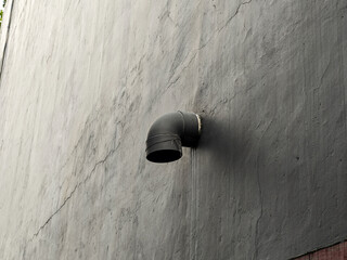 Poster - A gray wall with a black pipe protruding out of it provides a unique, textured backdrop, ideal for graphic design, urban art, or industrial projects. The texture of the wall creates visual interest.
