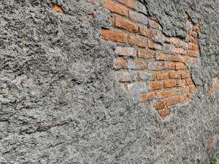Poster - Aged facade featuring exposed brickwork and heavily textured plaster, creating a contrast between the smoothness of the brick and the coarse surface, ideal for backgrounds and textures.