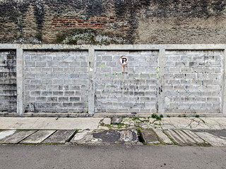Poster - Weathered brick wall beneath a textured surface contrasts with a block wall, adorned by a faded sign. The aging and decay suggest urban blight, perfect for gritty themes and raw realism.