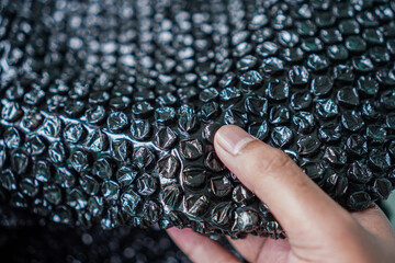 Poster - Close-up on bubble wrap being held, highlighting texture and protection. The finger gently presses against the surface, showing the material's tactile quality and cushioning capabilities.