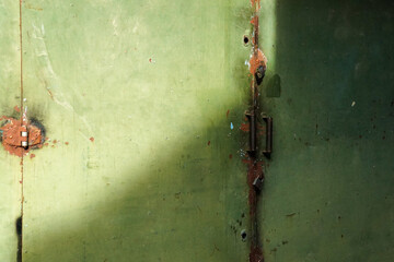 Poster - Rustic metal surface showcasing layers of faded green paint and textured rust, enhanced by a contrasting light shadow. The weathered pattern lends a vintage and industrial character.
