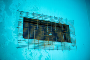Poster - A weathered aqua wall with a metal grid, evokes themes of confinement, protection, and industrial design. The peeling paint and aged metal add depth and texture. Perfect for backgrounds.