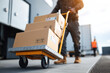 © Emanuel - Truck driver unloading boxes with hand truck at loading dock symbolizing delivery logistics and supply chain