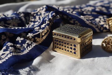 Poster - Elegant decorative box placed on embroidered fabric during a sunny afternoon in a cozy setting