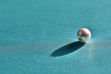 Poster - Glistening pearl resting on a turquoise surface during soft daylight