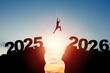 © Dilok - Welcome merry Christmas and happy new year in 2026,Silhouette Man jumping from 2025 cliff to 2026 cliff with cloud sky and sunlight.