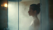 © Nattavee - A woman standing in a hot shower in the bathroom.