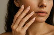 © Ajronujen - Woman showcasing manicured nails while touching her face in studio