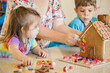 © Austockphoto - Kids decorating gingerbread house with lollies for christmas