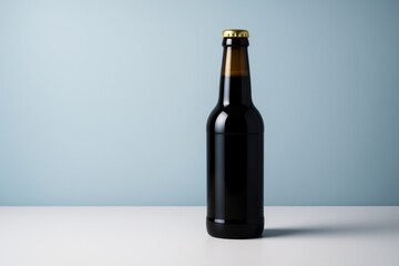 Poster - Dark glass drink bottle with gold cap on white surface against blue background for branding mockup or advertising template concept.