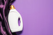© New Africa - Bottle of fabric softener and color cloth on purple background, top view. Space for text