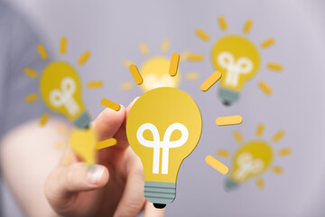 Aufkleber - Conceptual image of a hand holding a glowing lightbulb, symbolizing ideas, innovation, and creativity.
