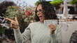 © Krakenimages.com - Woman smiling outdoors holding uae dirham banknote, pointing excitedly on a city street.