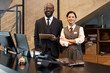 © pressmaster - Friendly hotel staff in formal attire greeting guests at reception desk Embracing hospitality with warm smiles and professional demeanor, ready to assist guests