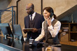 © pressmaster - Two colleagues collaborating at an office desk, with one man holding tablet and woman using phone. Modern and professional workspace background giving a productive atmosphere