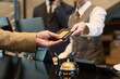 © pressmaster - Receptionist taking credit card from guest at hotel reception for transaction processing. Elegant setup with polished service tools like bell and pen holder visible on counter