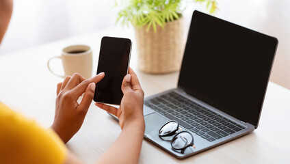 Poster - Workplace And Workspace. Over The Shoulder View Of Unrecognizable Black Lady Holding Mobile Phone With Blank Empty Screen For Mock Up Template, Sitting At Table With Computer, Plant And Coffee