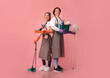© Prostock-studio - Cleaning Services Concept. Happy young couple holding lots of detergents, posing over pink background in studio, ready for spring-clean, copy space