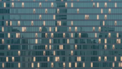 Poster - Night scene capturing dedicated employees working late in modern skyscraper, silhouetted against illuminated windows with urban cityscape backdrop