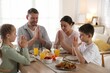© New Africa - Family praying together before dinner at table indoors