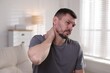 © New Africa - Man suffering from neck pain at home