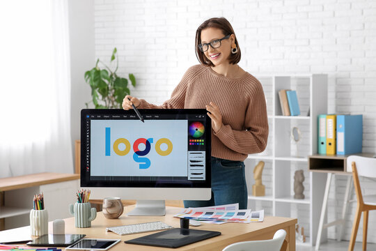 Young female graphic designer near computer with stylish logo in office