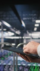 Poster - vertical video close up of data center software developer doing maintenance tasks on tablet, ensurin