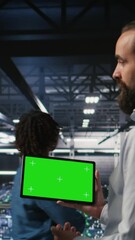 Poster - Vertical video Military technicians in data center use green screen mockup tablet to monitor systems. Army operators in server room ensuring stable infrastructure using chroma key device, camera A