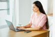 © Oleg Gekman - Beautiful young woman working with laptop computer in home kitchen. Work at home. Freelance, remote work