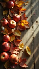 Poster - Autumn Harvest: Red Apples and Golden Leaves on Rustic Wooden Surface, Bathed in Sunlight