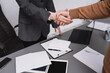 © illustrissima - Client shakes hands with lawyer, notary statue of Themis close-up on table in lawyer's office. Conclusion of deal, legislationDeal successful, signing of contract