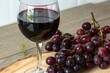 © valentina - glass of red wine with grapes on wooden table