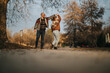 © qunica.com - A joyful couple shares a dance in a serene autumn park, expressing romance and happiness. The surrounding fall foliage creates a warm, natural backdrop, complementing their connection and love.
