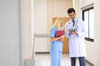 © NVB Stocker - Multi-ethnic healthcare workers in hospital. nurse and doctor walking in corridor and  talking and in discussion for advice, medical service, diagnosis and consulting