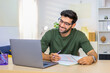 © unikyluckk - Man enjoying a productive work session from modern living space. Young man working at home. Home office., freelance. Focused handsome freelancer doing online research over laptop.