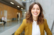 © Andrii Zastrozhnov - A woman in a yellow jacket and white shirt is smiling. She is standing in a hallway with a few other people