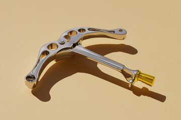 Poster - Unique chrome-colored tool resting on a yellow background showcasing design and craftsmanship in a minimalistic style