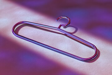 Poster - Colorful metallic hanger resting on a soft surface illuminated by vibrant light patterns in an artistic setup