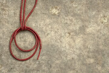 Poster - Red string loop placed on a textured gray background displaying simplicity and elegance in design