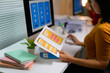 © Parichat - Asian woman working as UX/UI designer holding mobile app templates comparing them with computer screen