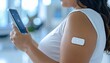 © Igor_Tichonow - Woman using wearable health patch and smartphone highlights smart health tracking and personal tech evolution