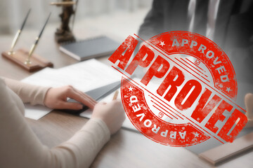 Fototapete - Woman signing document at table in office and red stamp Approved