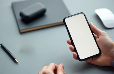 Poster - Close up of hand holding smartphone with blank screen. Business, communication concept. Digital tech device, modern gadget for web surfing, apps. Office desk with notepad, pen and mouse.