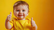 © Gayane - Smiling toddler boy in a yellow shirt giving a thumbs up, set against a pastel background with copy space—cheerful, ultra-realistic portrait full of joy...