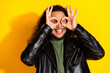 © deagreez - Cheerful young man in leather jacket making playful hand gestures on vibrant yellow background