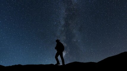 Wall Mural - hiker silhouette stands on the hill on the milky way galaxy background. night tight landscape starry