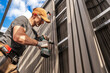 © Tomasz Zajda - Construction Worker Installing Lamella Composite Panels on a Building During a Sunny Day in a Suburban Area