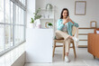 © Pixel-Shot - Young woman with nose piercing using mobile phone in chair at home