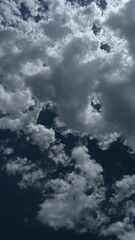 Wall Mural - Vertical time timelapse of fluffy white to gray cumulus clouds moving across a blue summer sky
