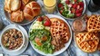 © Sajeel - An overhead shot of a table filled with various breakfast foods including waffles and croissants